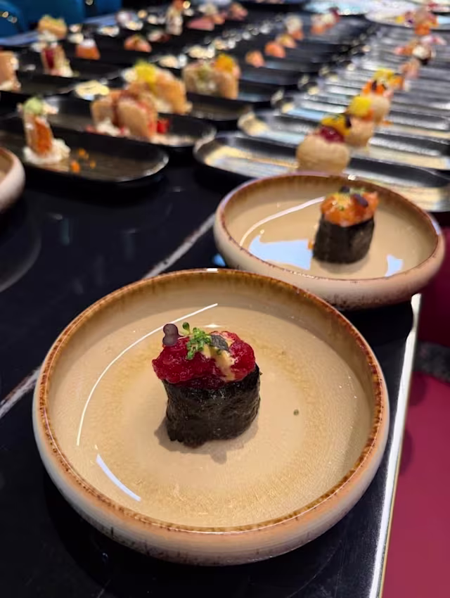 Sushi joliment présenté avec un monticule de riz surmonté d'une couche d'œufs de poisson rouge et de fines herbes hachées, enveloppé dans une bande d'algue.